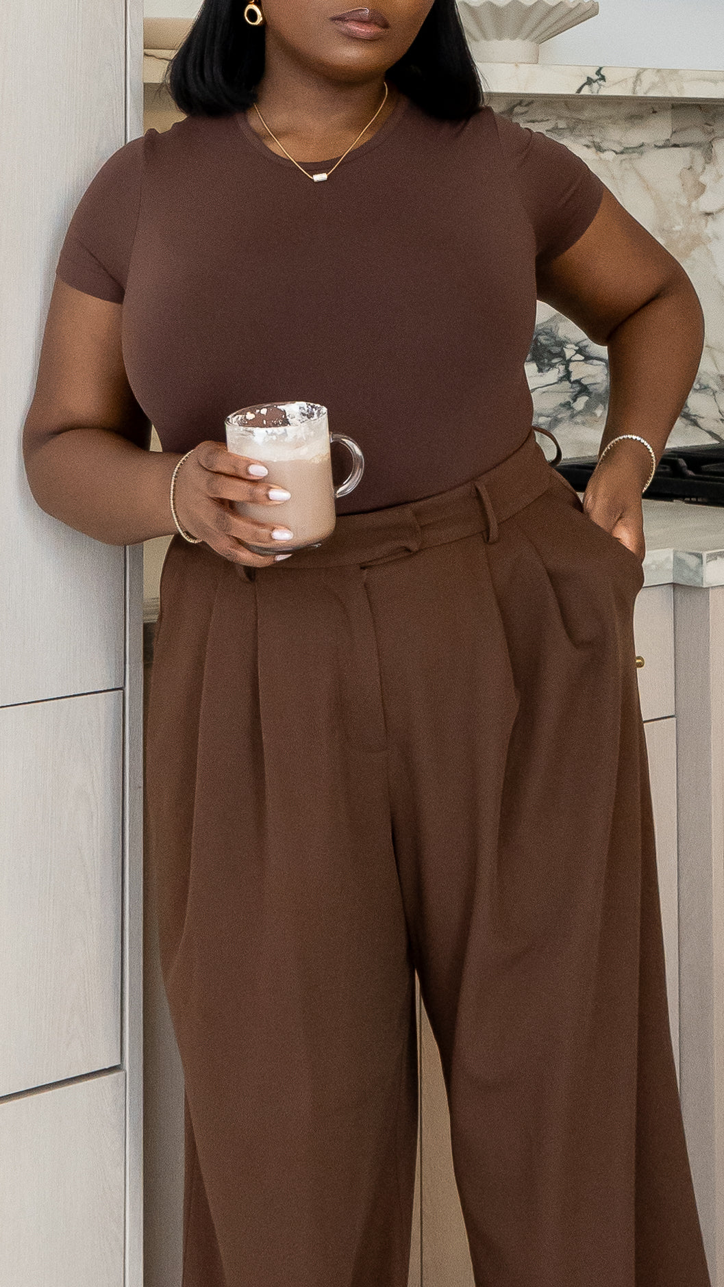Full-body indoor shot of model in structured chocolate trousers