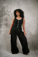 Woman wearing a black outfit with gold buttons against a gray background