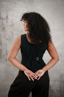 Woman wearing a black sleeveless top and pants against a gray background